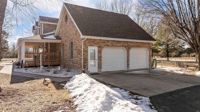 snow covered property featuring a garage and covered porch