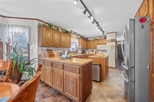 kitchen with track lighting, stainless steel fridge, a center island, and sink