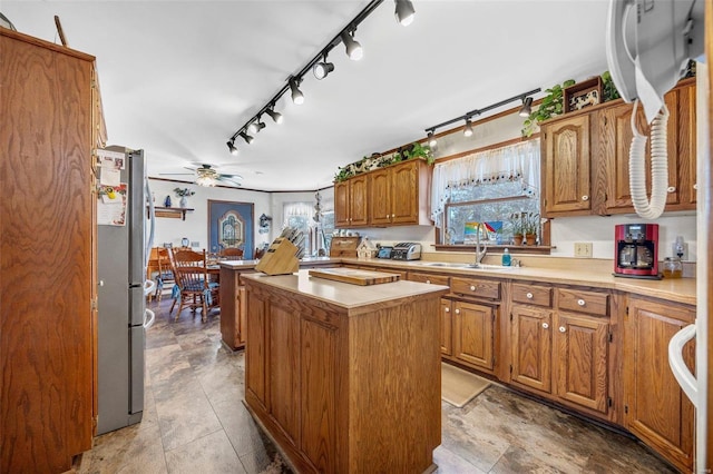 kitchen featuring a kitchen island, stainless steel refrigerator, sink, ceiling fan, and track lighting