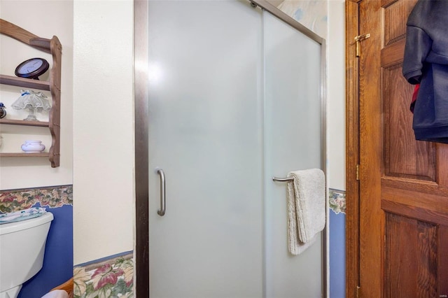 bathroom featuring a shower with door and toilet