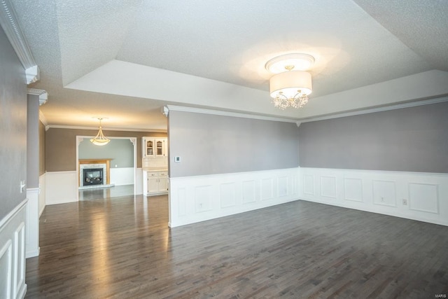 spare room featuring lofted ceiling, ornamental molding, a textured ceiling, dark hardwood / wood-style flooring, and a raised ceiling