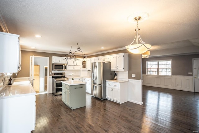 kitchen with a kitchen island, decorative light fixtures, white cabinetry, sink, and stainless steel appliances