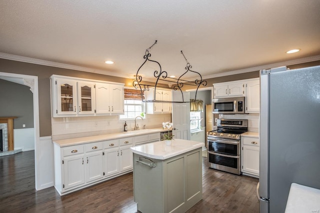 kitchen featuring sink, white cabinetry, hanging light fixtures, appliances with stainless steel finishes, and a kitchen island