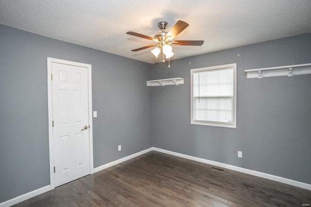 empty room featuring ceiling fan, dark hardwood / wood-style floors, and a textured ceiling