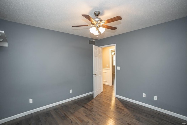 spare room featuring dark hardwood / wood-style floors, a textured ceiling, and ceiling fan