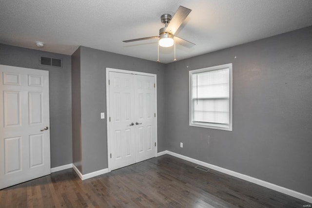 unfurnished bedroom featuring ceiling fan, dark hardwood / wood-style flooring, a closet, and a textured ceiling