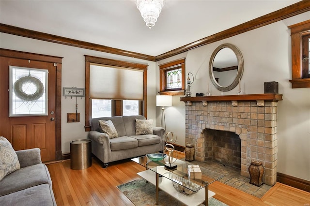 living room featuring a brick fireplace, crown molding, baseboards, and wood finished floors