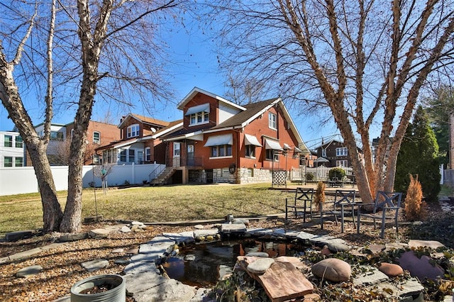 back of property featuring a residential view, a lawn, and fence