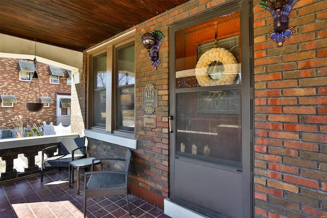 property entrance with covered porch and brick siding