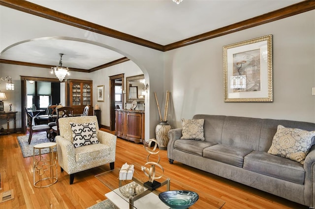 living room featuring arched walkways, plenty of natural light, wood finished floors, and an inviting chandelier