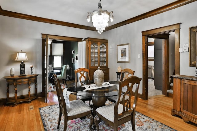 dining area featuring light wood-style flooring, ornamental molding, a chandelier, and baseboards