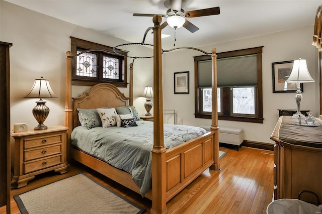 bedroom with light wood finished floors, baseboards, and a ceiling fan