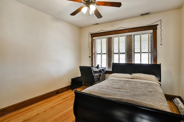 bedroom featuring baseboards, visible vents, ceiling fan, and wood finished floors