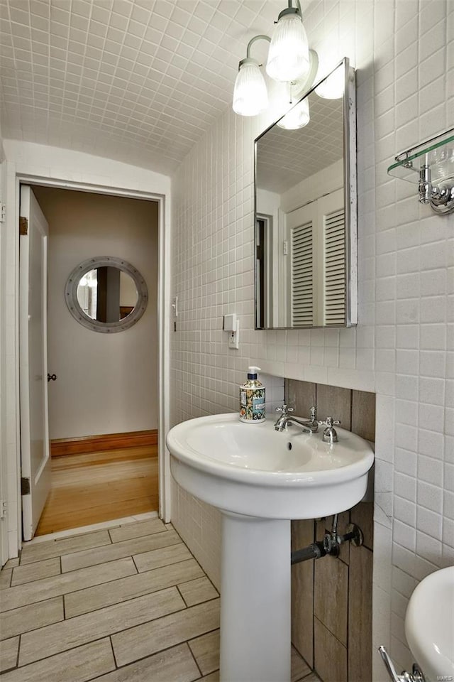 bathroom with wood finish floors, tile walls, and baseboards