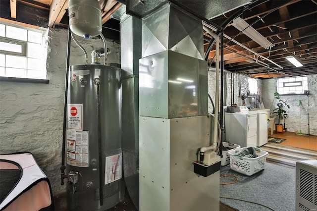 utility room with gas water heater, heating unit, and separate washer and dryer