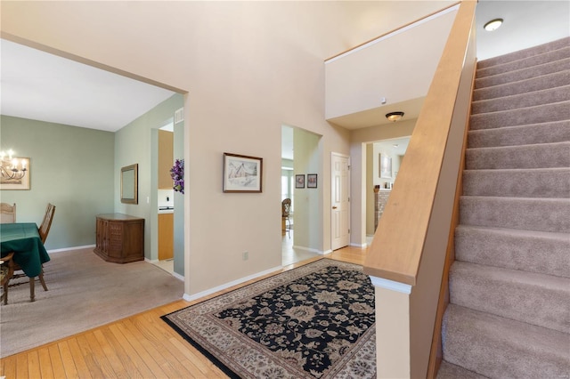 foyer featuring wood-type flooring, stairway, a chandelier, and baseboards