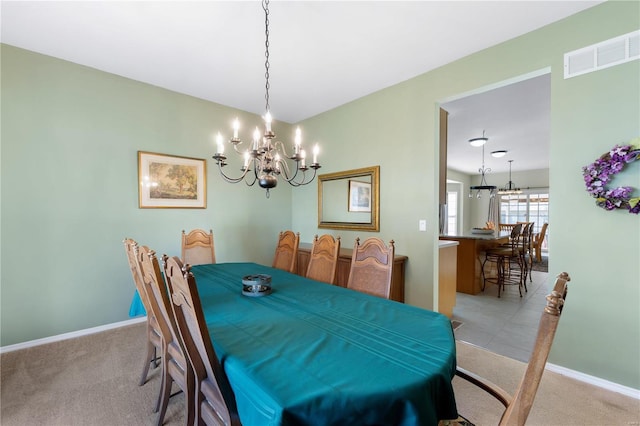 dining space featuring light colored carpet, visible vents, baseboards, and an inviting chandelier