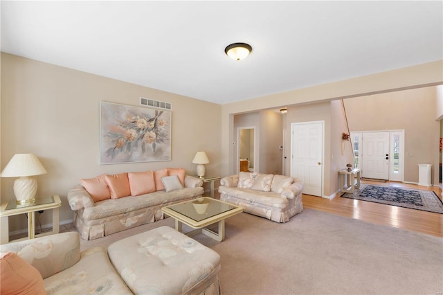 living room with carpet floors, visible vents, baseboards, and wood finished floors