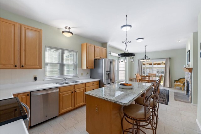 kitchen with a fireplace, a breakfast bar area, stainless steel appliances, a sink, and a kitchen island