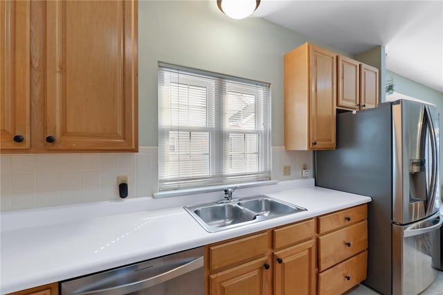 kitchen with appliances with stainless steel finishes, light countertops, a sink, and tasteful backsplash