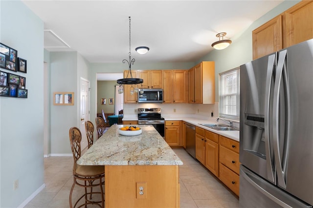 kitchen featuring light tile patterned floors, a kitchen island, appliances with stainless steel finishes, a kitchen bar, and a sink