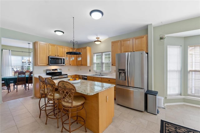 kitchen with light tile patterned floors, a center island, stainless steel appliances, a kitchen bar, and a sink