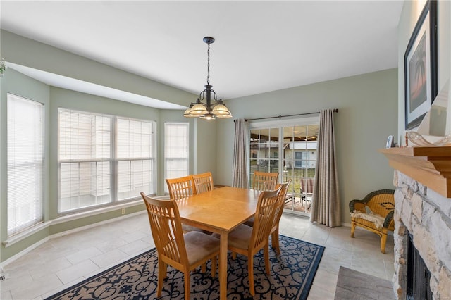 dining space featuring light tile patterned flooring, a fireplace, a notable chandelier, and baseboards