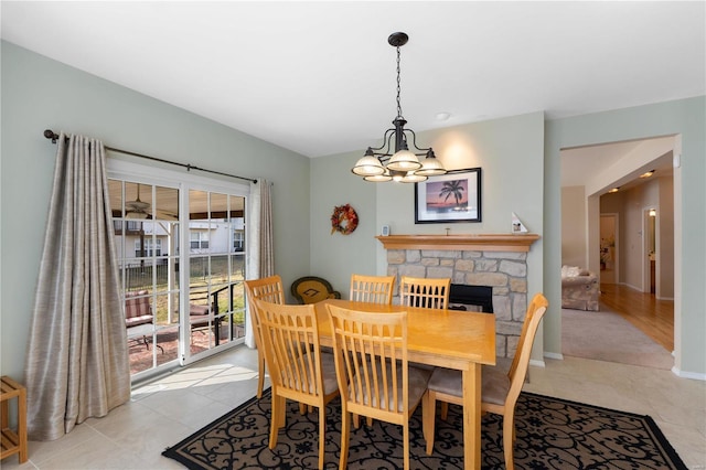 dining room with baseboards, light tile patterned flooring, a fireplace, and a notable chandelier