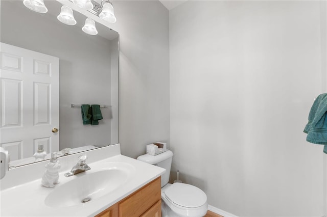 bathroom featuring baseboards, vanity, and toilet