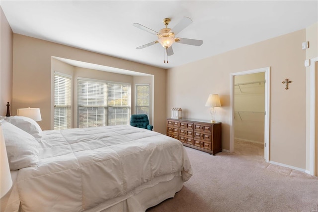 bedroom featuring carpet, ceiling fan, a spacious closet, and baseboards