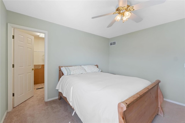 carpeted bedroom featuring baseboards, visible vents, a walk in closet, and a ceiling fan