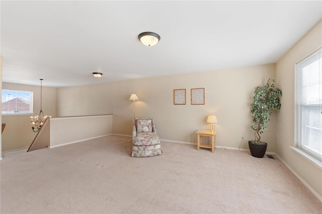 unfurnished room featuring a healthy amount of sunlight, carpet, and an inviting chandelier