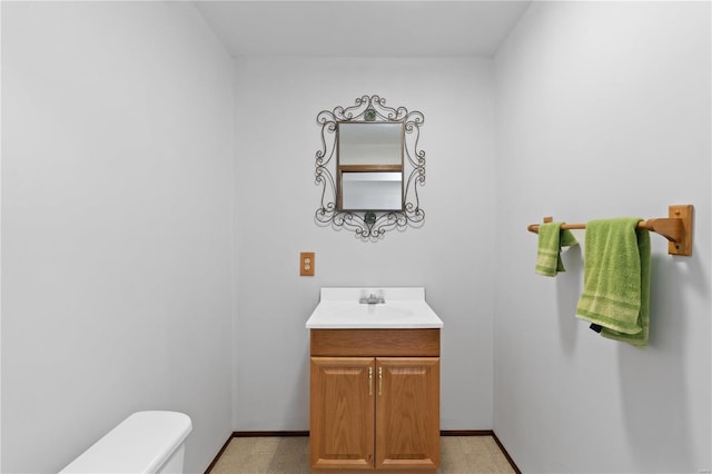 bathroom featuring toilet, baseboards, and vanity