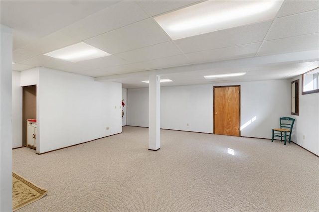 below grade area with a paneled ceiling and carpet