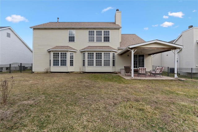 rear view of property featuring a patio area, a yard, a chimney, and fence