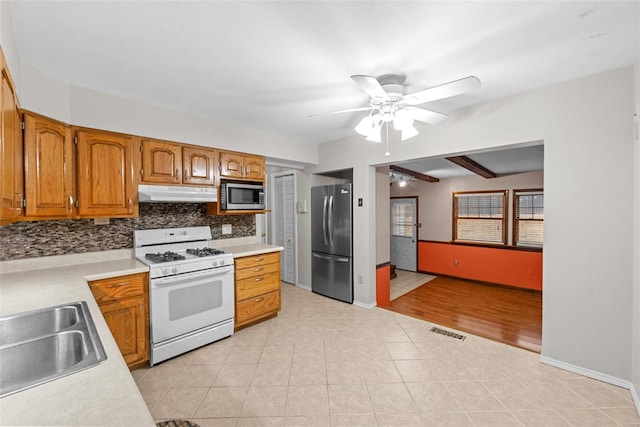 kitchen featuring sink, light tile patterned floors, appliances with stainless steel finishes, ceiling fan, and decorative backsplash