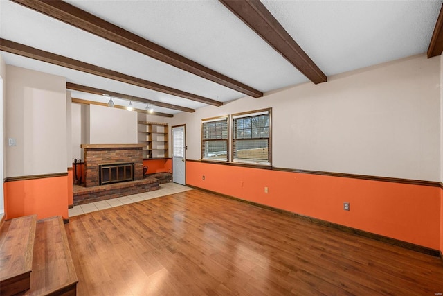 living room with beamed ceiling, a fireplace, and light hardwood / wood-style flooring