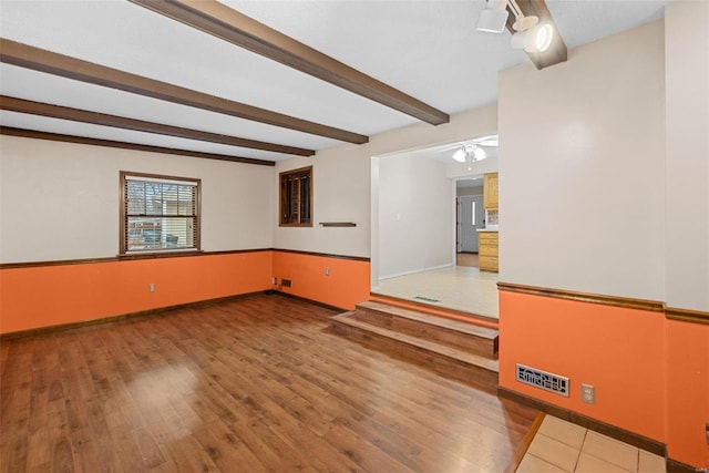 unfurnished room featuring wood-type flooring and beam ceiling