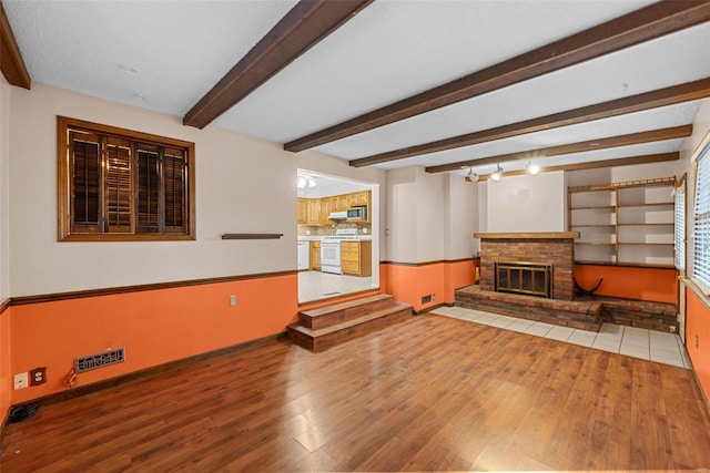 living room featuring beam ceiling, wood-type flooring, and a fireplace