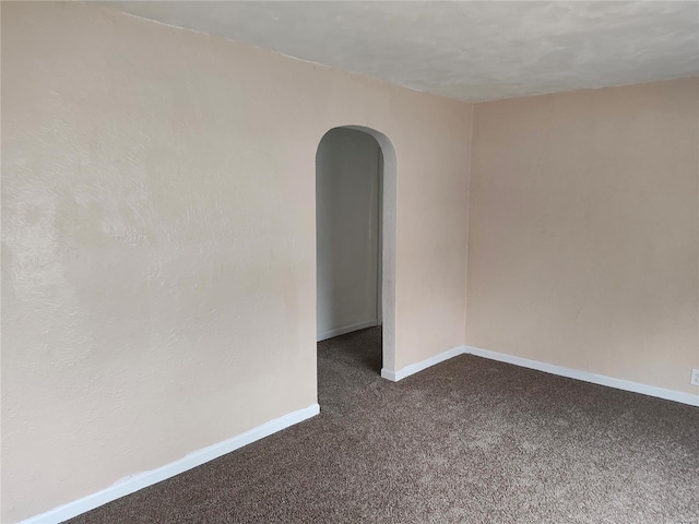 spare room featuring dark colored carpet