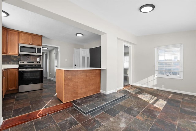 kitchen with tasteful backsplash, appliances with stainless steel finishes, and kitchen peninsula