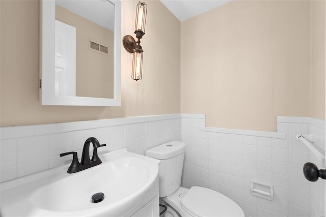 bathroom featuring toilet, sink, and tile walls