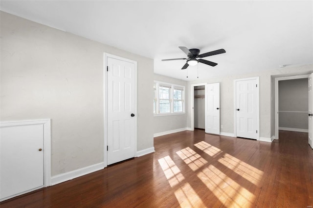 unfurnished bedroom with multiple closets, ceiling fan, and dark hardwood / wood-style floors