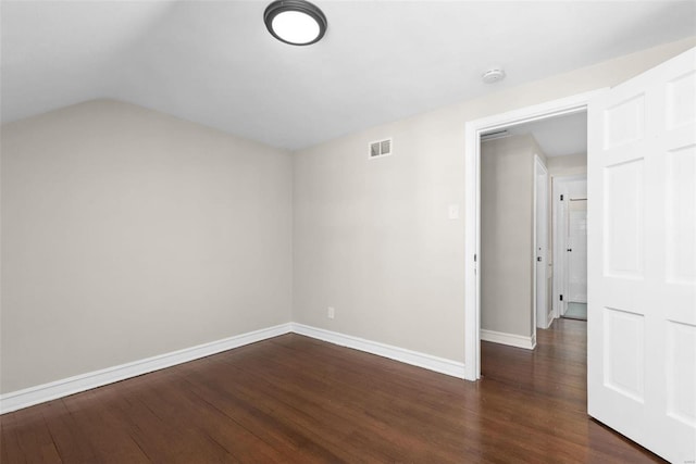 unfurnished room featuring lofted ceiling and dark hardwood / wood-style flooring