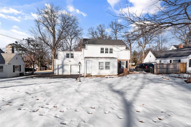 snow covered house featuring a garage