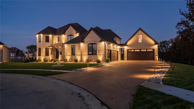 french country style house featuring brick siding, a front lawn, and concrete driveway