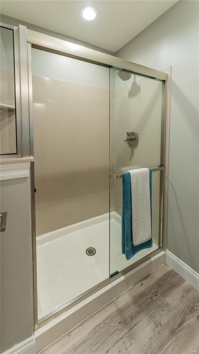 bathroom with baseboards, a shower stall, recessed lighting, and wood finished floors