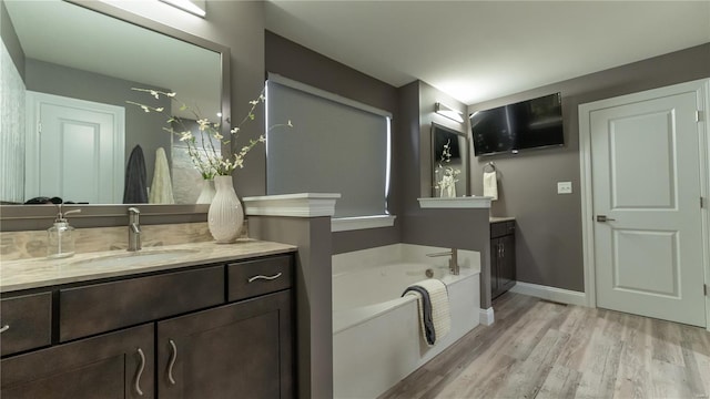 full bathroom with baseboards, wood finished floors, a garden tub, and vanity