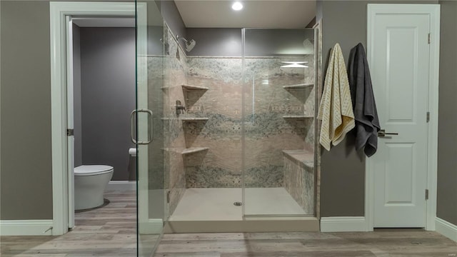 bathroom featuring baseboards, a stall shower, toilet, and wood finished floors