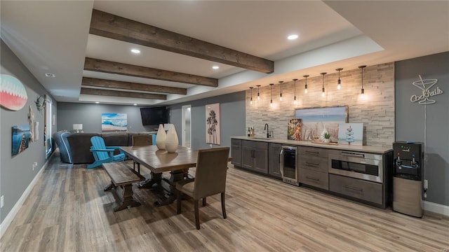 interior space with beverage cooler, light wood-style flooring, baseboards, and wet bar